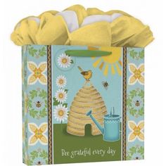 a blue and yellow gift bag with bees, sunflowers and a beehive