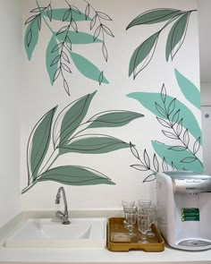 a kitchen wall with leaves painted on it and a toaster next to the sink