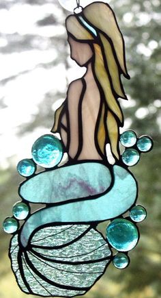 a stained glass mermaid hanging from a window