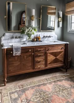 a bathroom with two sinks, mirrors and rugs on the floor in front of it