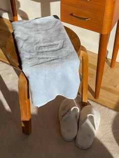 a pair of slippers sitting on top of a chair next to a white towel