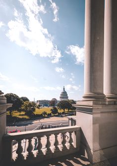 the capital building in washington, d c is seen from behind some white pillars and columns