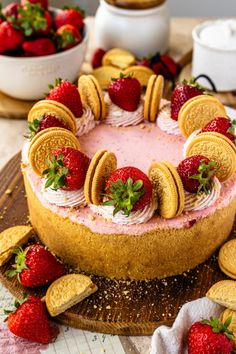 a cake with cookies and strawberries is on a wooden platter next to other desserts