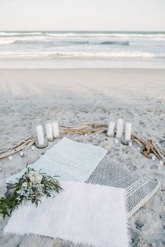 a white blanket and candles on the beach