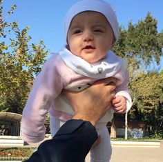 a man holding a baby in his arms while wearing a pink shirt and white head scarf