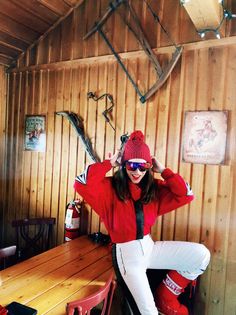 a woman sitting at a table with skis on top of her head and wearing sunglasses