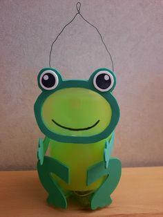 a green frog sitting on top of a wooden table