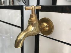 a brass faucet is mounted on the side of a white and black cabinet