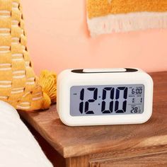 an alarm clock sitting on top of a wooden table next to a yellow throw pillow