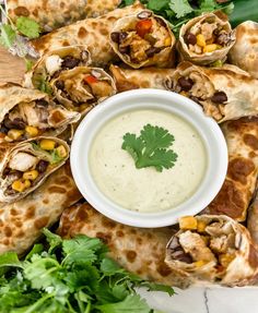 a platter filled with tortillas covered in guacamole and garnished with cilantro