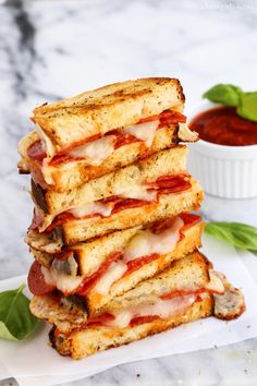 a stack of sandwiches sitting on top of a white plate next to a bowl of ketchup