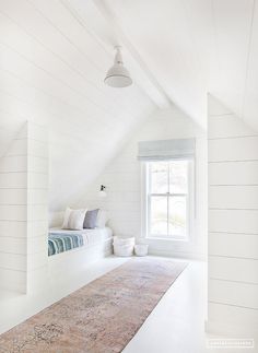 a bedroom with white walls and floors has a large rug on the floor in front of the window