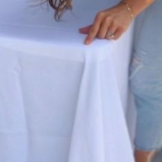 a woman holding onto a white table cloth