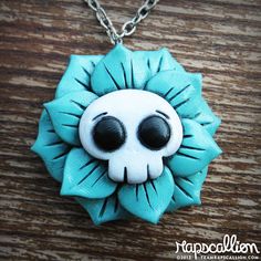 a blue and white flower with black eyes on a wooden table next to a chain