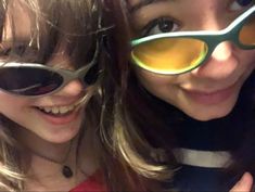 two girls wearing sunglasses and smiling for the camera