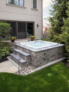 a hot tub sitting in the middle of a yard next to a house with stairs leading up to it