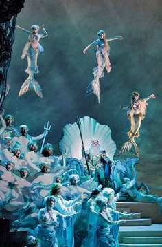 the stage is decorated with blue and white mermaids as well as people dressed in costumes