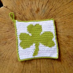 a green and white crocheted pot holder on top of a wooden table next to a piece of wood