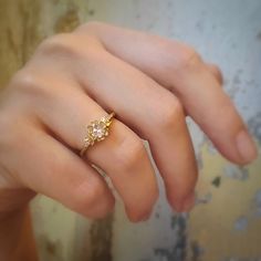 a woman's hand wearing a gold ring with two diamonds on the middle finger