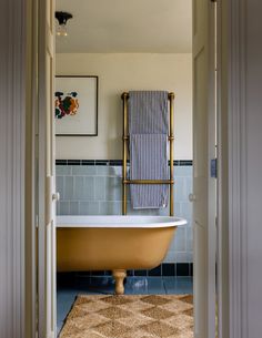 a bathroom with a claw foot bathtub and blue tiled walls, along with a rug on the floor