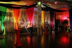 an image of a party setting with colorful lights and drapes on the wall behind the dance floor