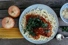 a plate of spaghetti with tomato sauce, parmesan cheese and garlic on the side