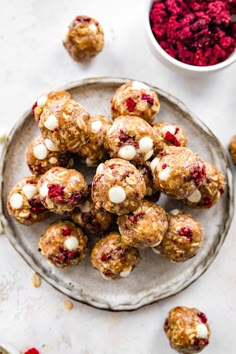 a plate full of cranberry energy bites next to a bowl of cranberries