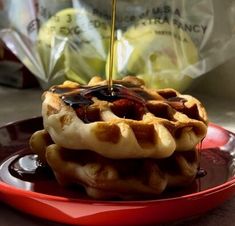 waffles with syrup being drizzled over them on a red plate