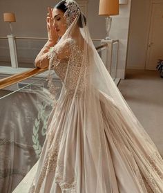 a woman in a wedding dress is standing on the stairs with her hand up to her face