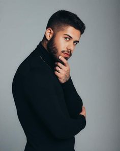 a man with a beard and piercing on his head is posing for the camera while wearing a black turtle neck sweater