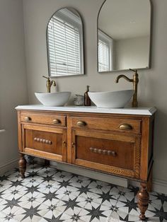 two sinks sit on top of a wooden cabinet in front of mirrors and a tiled floor