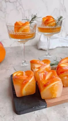 several orange slices on a cutting board next to some wine glasses