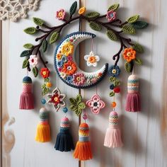 a crocheted wall hanging with flowers and tassels attached to the outside of it