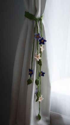 a curtain with flowers hanging from it's side in front of a white curtain