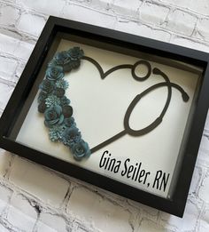 a shadow frame with a stethoscope in the shape of a heart and flowers