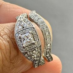 a close up of a person's hand holding an engagement ring with diamonds on it