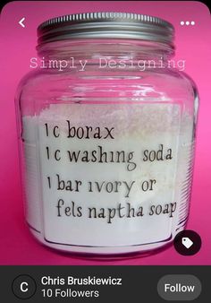 a jar filled with lots of white stuff on top of a pink table next to a wall