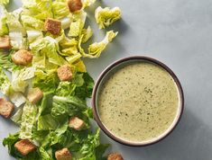 lettuce and croutons are next to a bowl of dressing