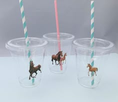 four plastic cups with horses on them and two drinking straws in the same cup