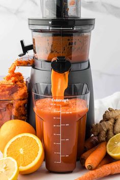 a blender filled with orange juice next to carrots and ginger