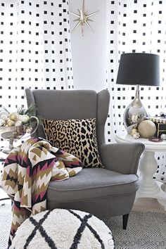 a living room with white walls and black and gold accessories on the table, leopard print throw pillow