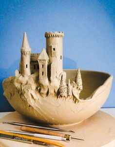 a clay castle sitting on top of a table next to some paintbrushes and an artist's palette