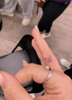 a person with a small butterfly tattoo on their finger