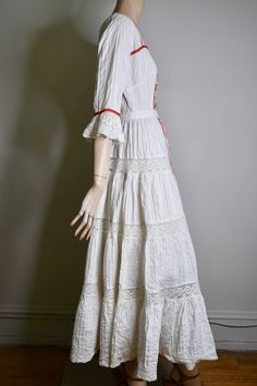 "This dress is so special. It is a vintage 60s/70s Mexican pin tucked white dress. The dress has a square neckline, that is trimmed with red ribbon and small lace ruffles, is fitted to the waist with a floral embroidered bodice that is also finished on the side with red ribbon, it has 3/4 sleeves with a flared lace cuff and red ribbon trim, The skirt is a long maxi skirt that is quite full, it has a front and back center panel with red ribbon running down the length, coming off the front panel i Fitted Broderie Anglaise Maxi Dress, Bohemian Lace Dress With Broderie Anglaise, Bohemian Prairie Dress With Lace Trim For Wedding, Bohemian Prairie Wedding Dress With Lace Trim, Bohemian Cotton Dresses With Broderie Anglaise, Vintage Lace Festival Dresses, Bohemian Maxi-length Prairie Dress For Garden Party, Bohemian Prairie Maxi Dress For Garden Party, Bohemian Maxi Prairie Dress For Garden Party