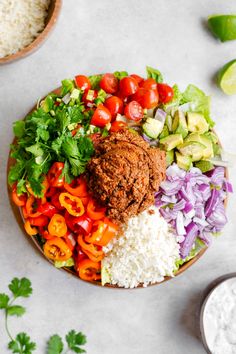 a plate filled with rice, meat and vegetables next to some dipping sauce on the side