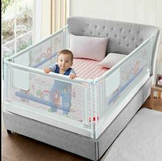 a baby sitting in a crib with pillows on the floor