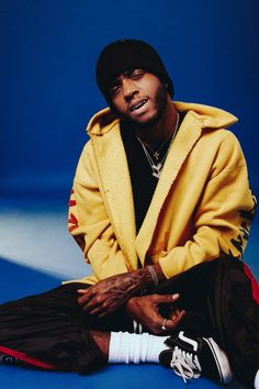 a man sitting on the ground wearing a yellow jacket