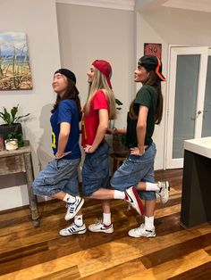 three young people standing in a room with wooden floors