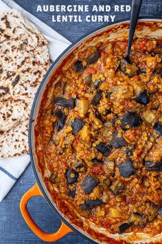 a large pot filled with food next to flatbreads on a blue tablecloth