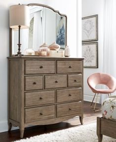 a bedroom scene with focus on the dresser and mirror in the foreground, along with a chair